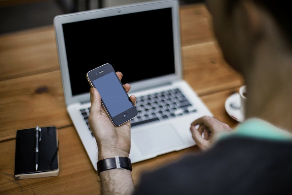 person with mobile phone and a laptop